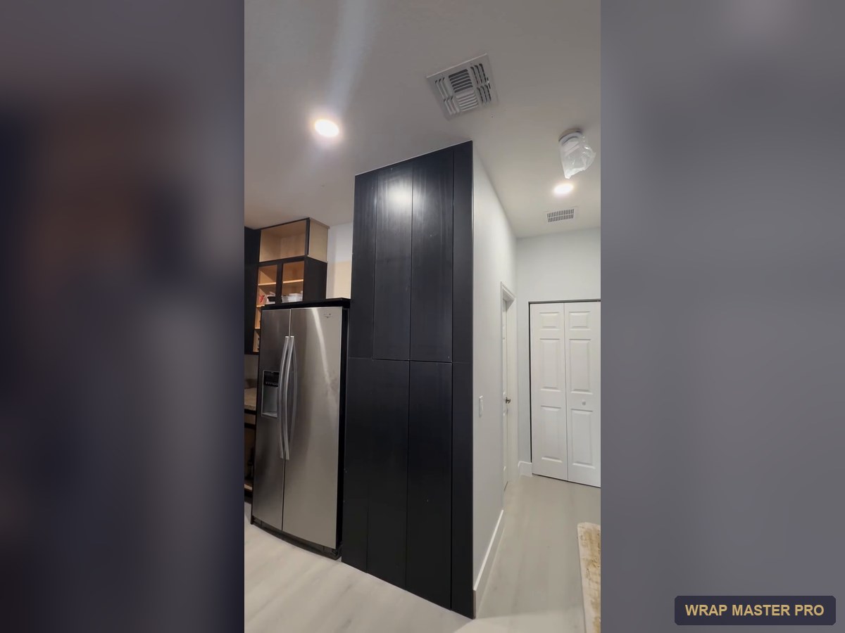 Floor-to-ceiling black woodgrain pantry wall beside the refrigerator, South Florida